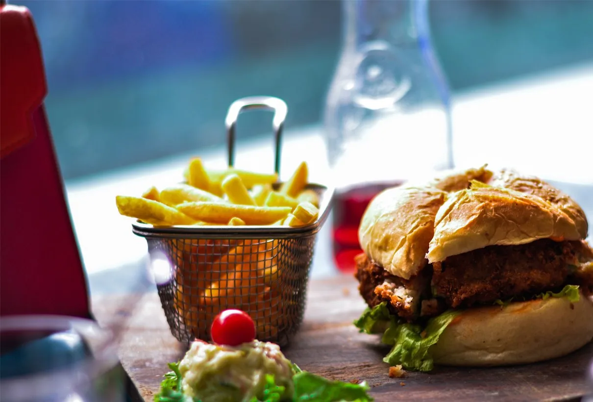 En hamburger med pommes frites i en liten korg på ett bord