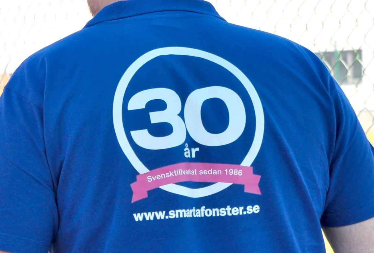 Ryggen på en blå tröja med märket ”30 år” och adressen smartafonster.se
