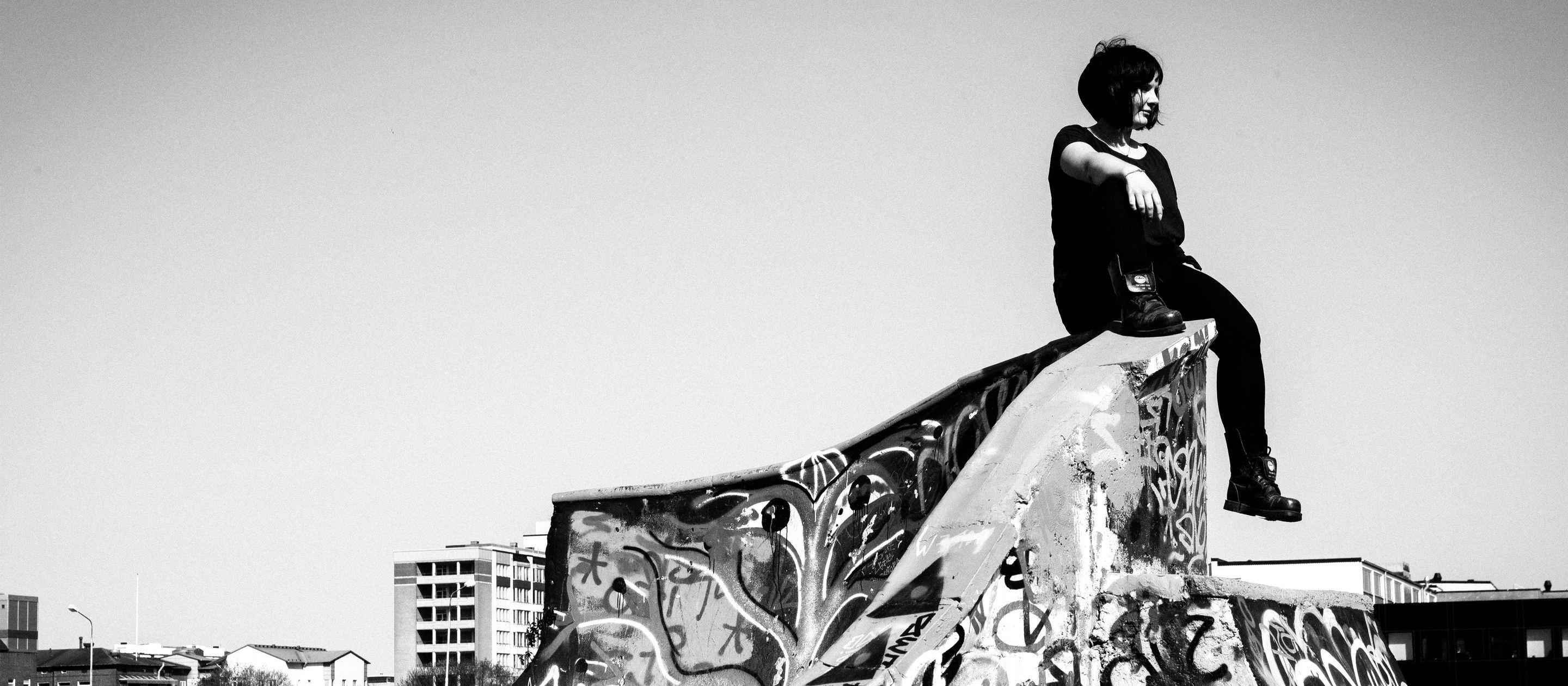 Svartvitt foto av en person som sitter på en kant i en graffitidekorerad skatepark