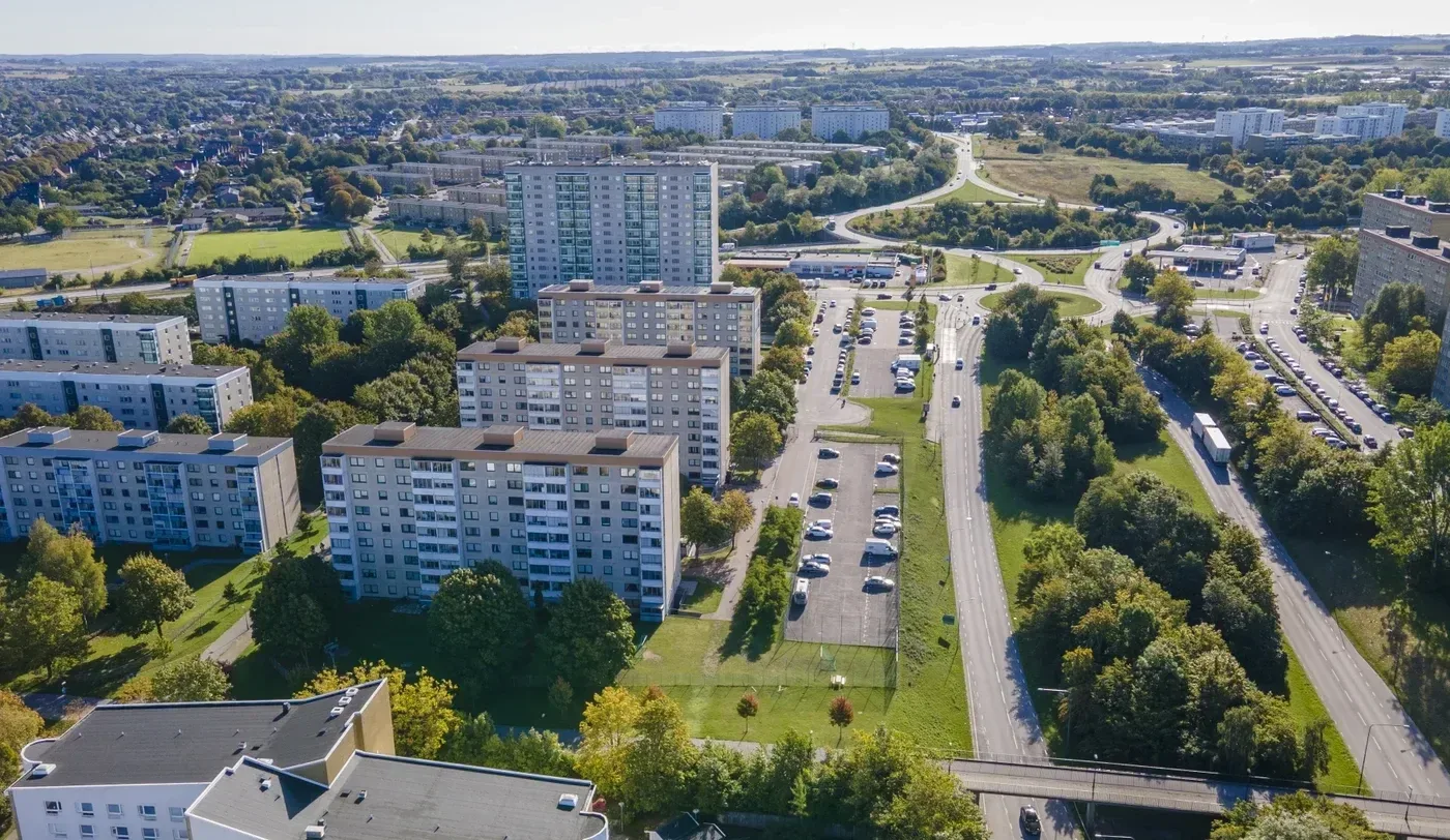 Flygbild över bostadshus, parkeringar och gröna ytor i ett bostadsområde