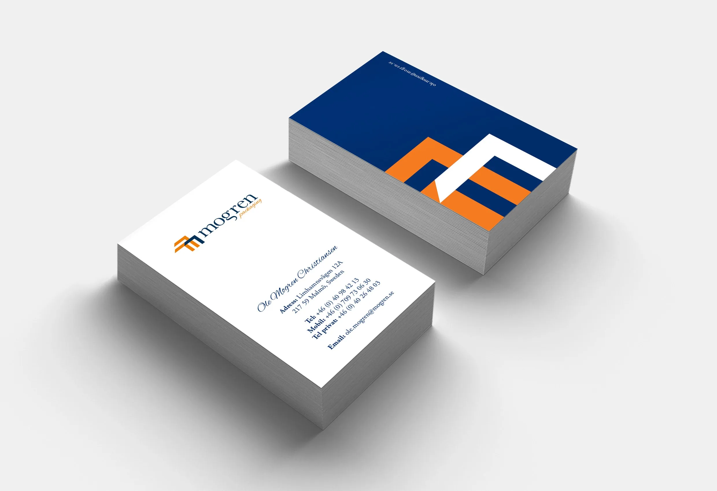 Två högar visitkort med Mogrens logotyp i blått, orange och vitt
