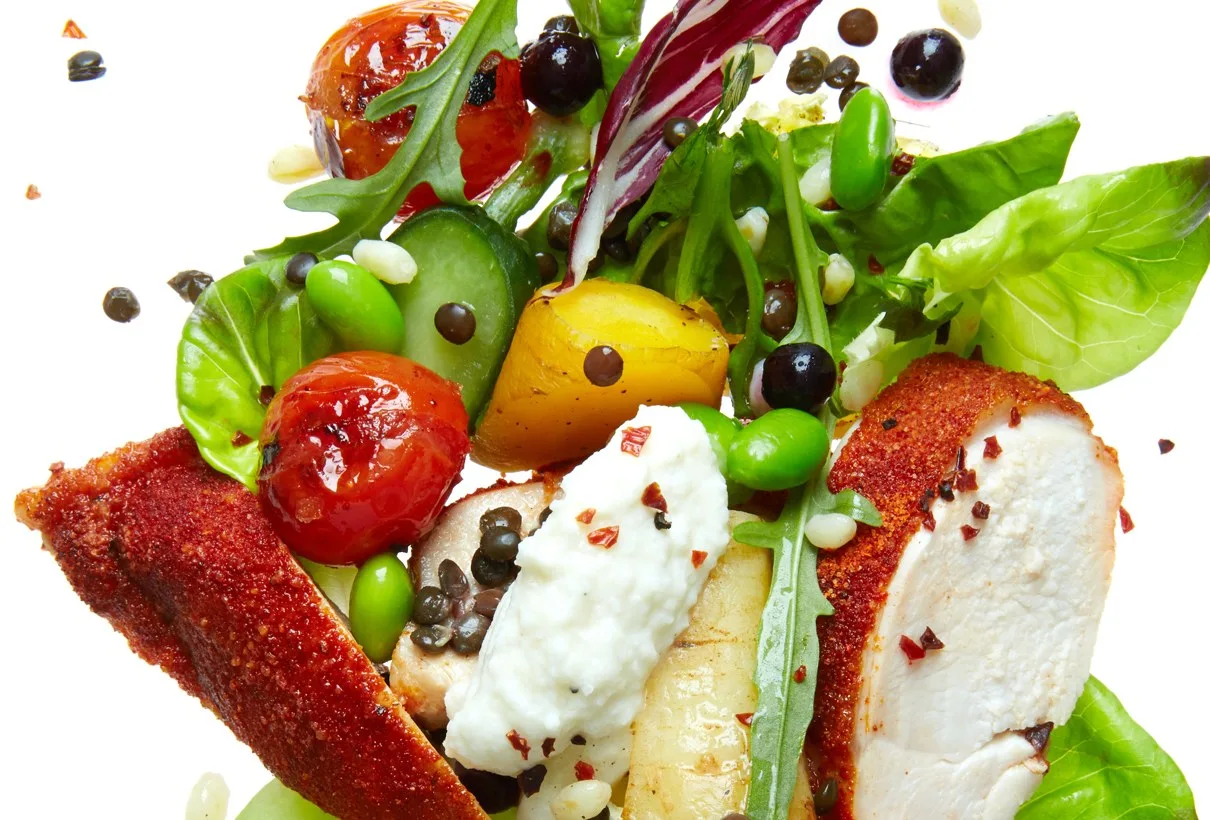 En sallad med stekt kyckling, tomater och bönor, sedd uppifrån