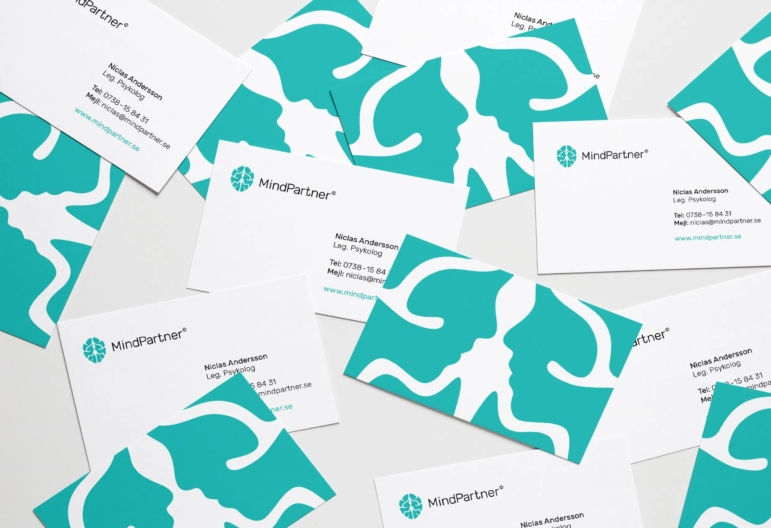 Spridda visitkort i turkost och vitt med MindPartners logotyp och ett mönster av två profiler