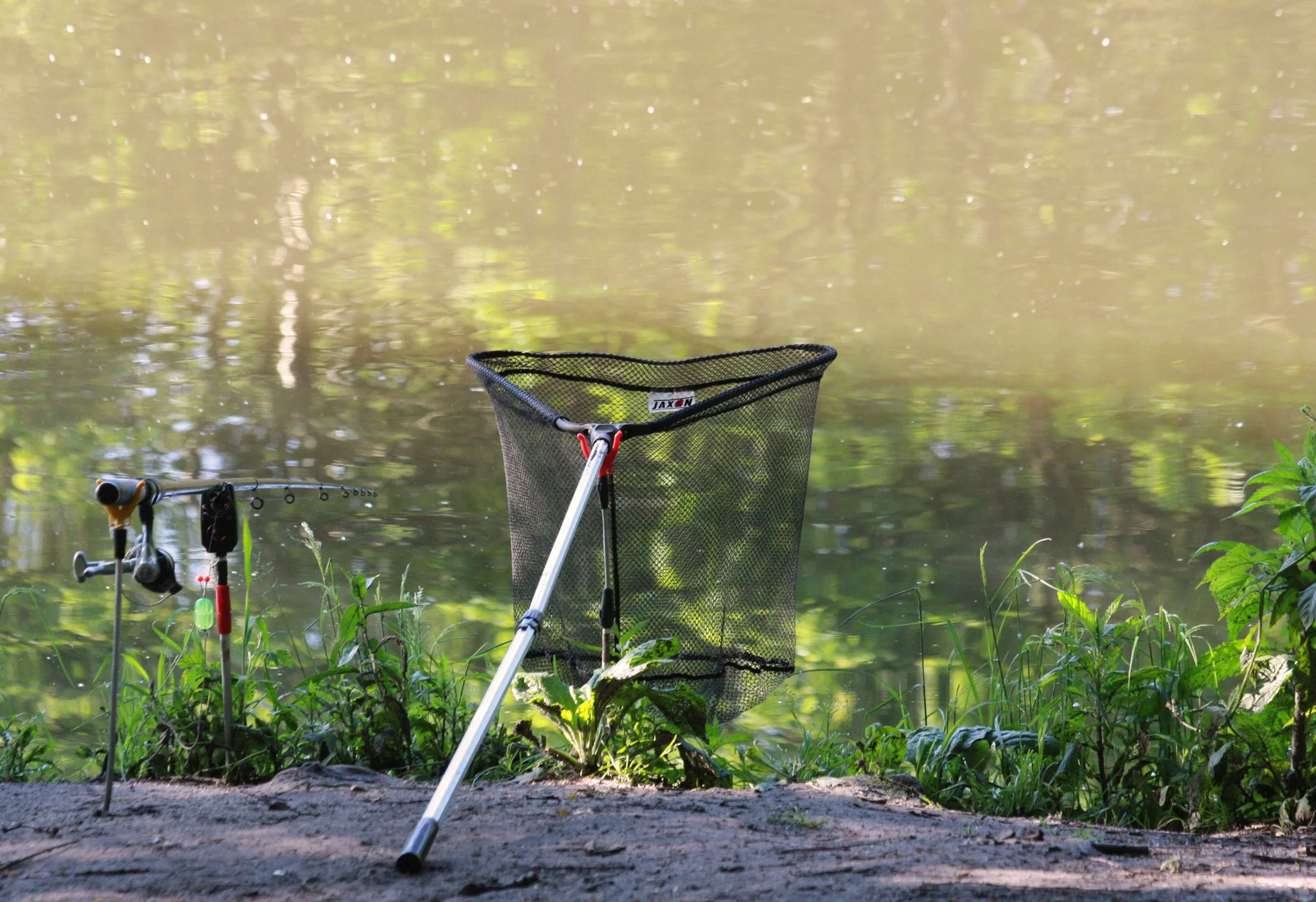 Ett hopfällbart fiskenät som står vid en strand med fiskeutrustning vid vattnet