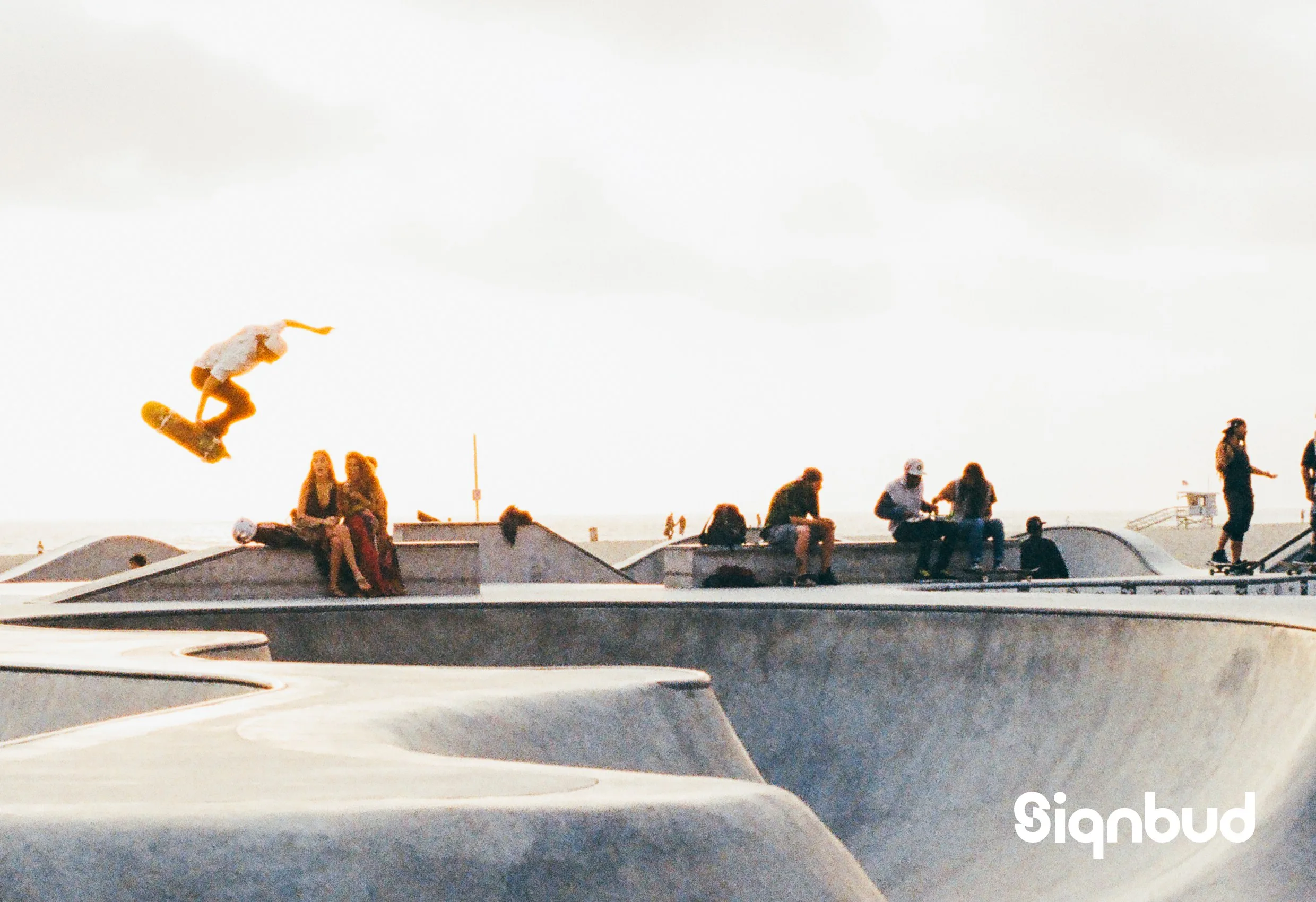 En skateboardåkare i luften vid en skatepark, med Signbuds logotyp nere till höger