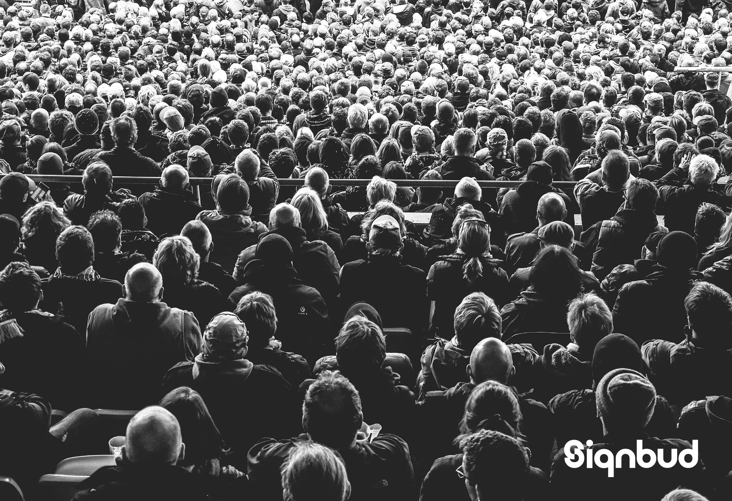 Svartvitt foto av en stor publik, med Signbuds logotyp nere till höger