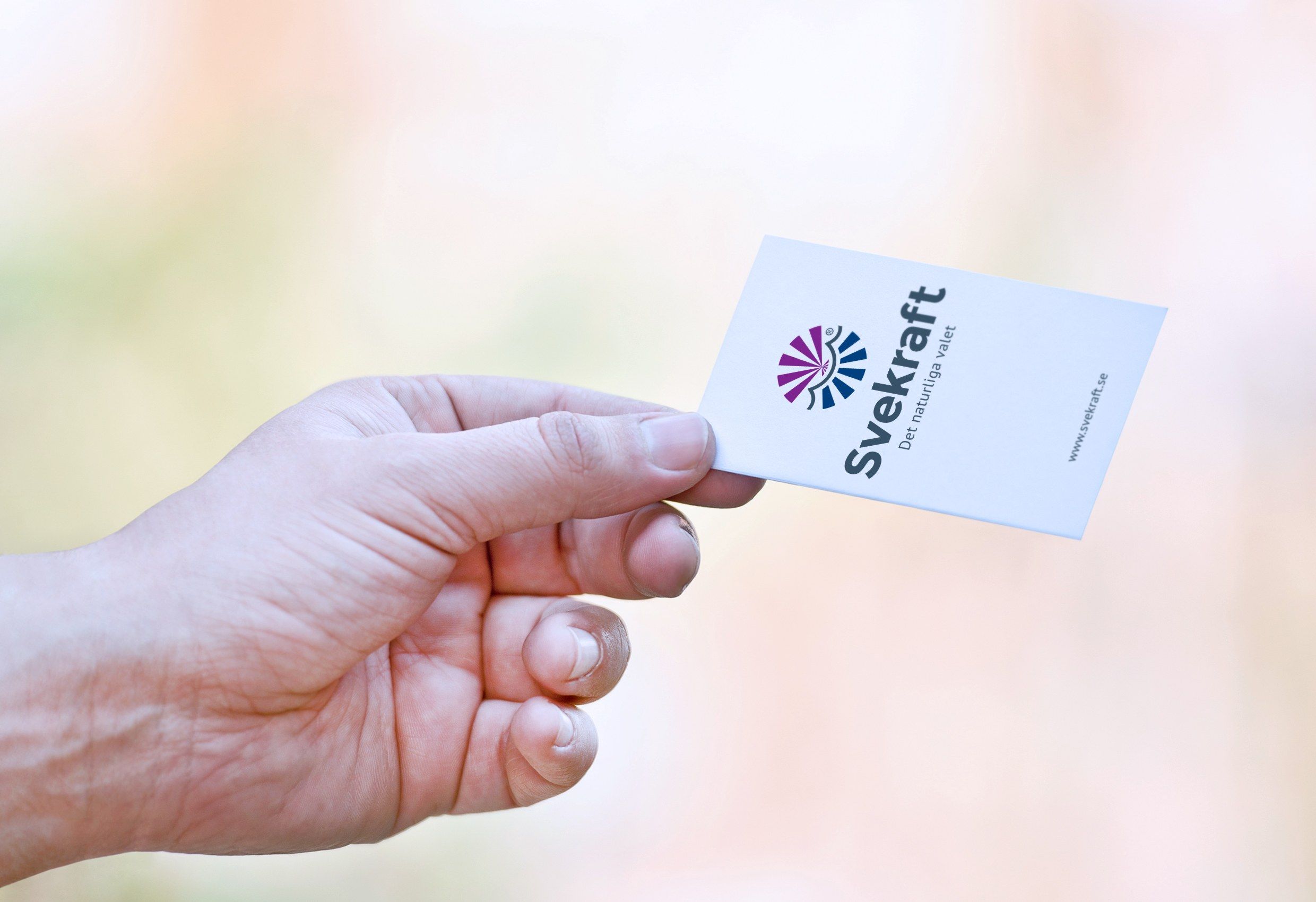 En hand som håller ett visitkort med Svekrafts logotyp