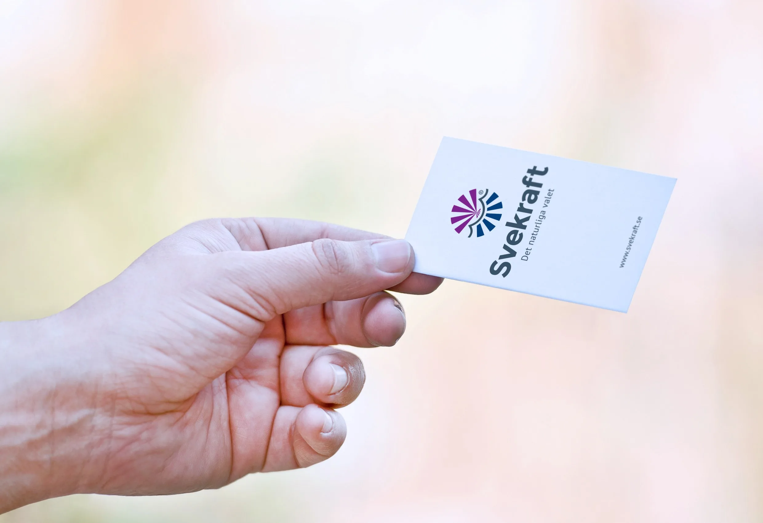 En hand som håller ett visitkort med Svekrafts logotyp