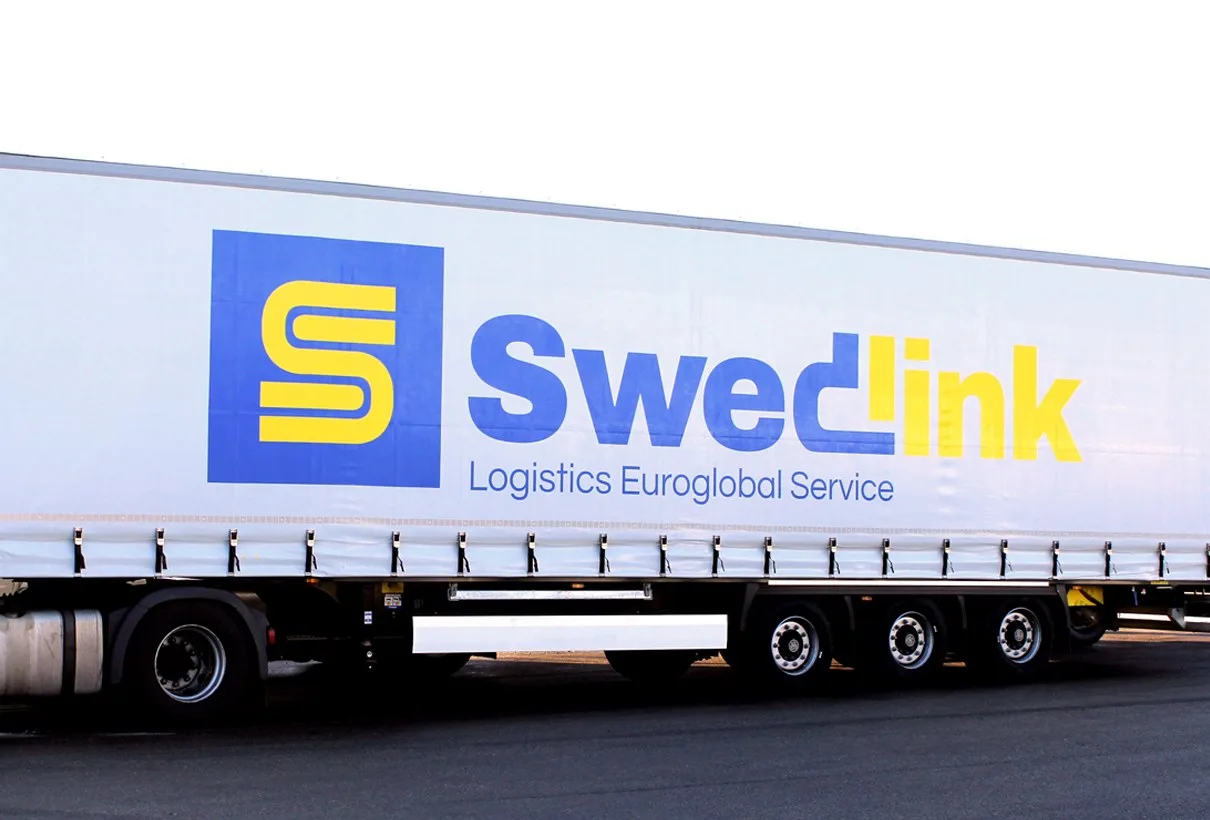 Närbild på sidan av en lastbilsbyggnad med Swedlinks logotyp och texten ”Logistics Euroglobal Service”