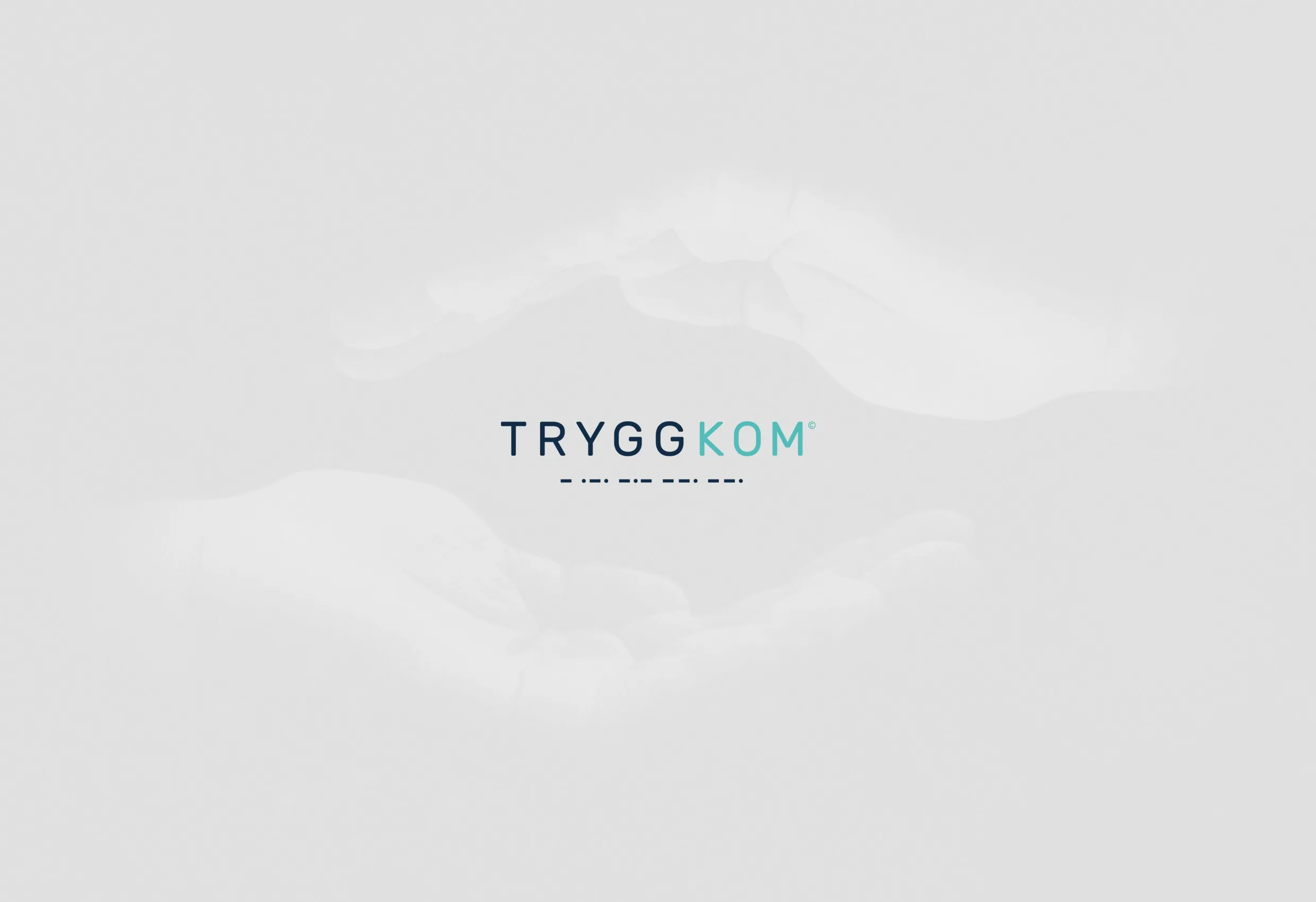 Logotypen Tryggkom i mörkt på en dunkig grå bakgrund