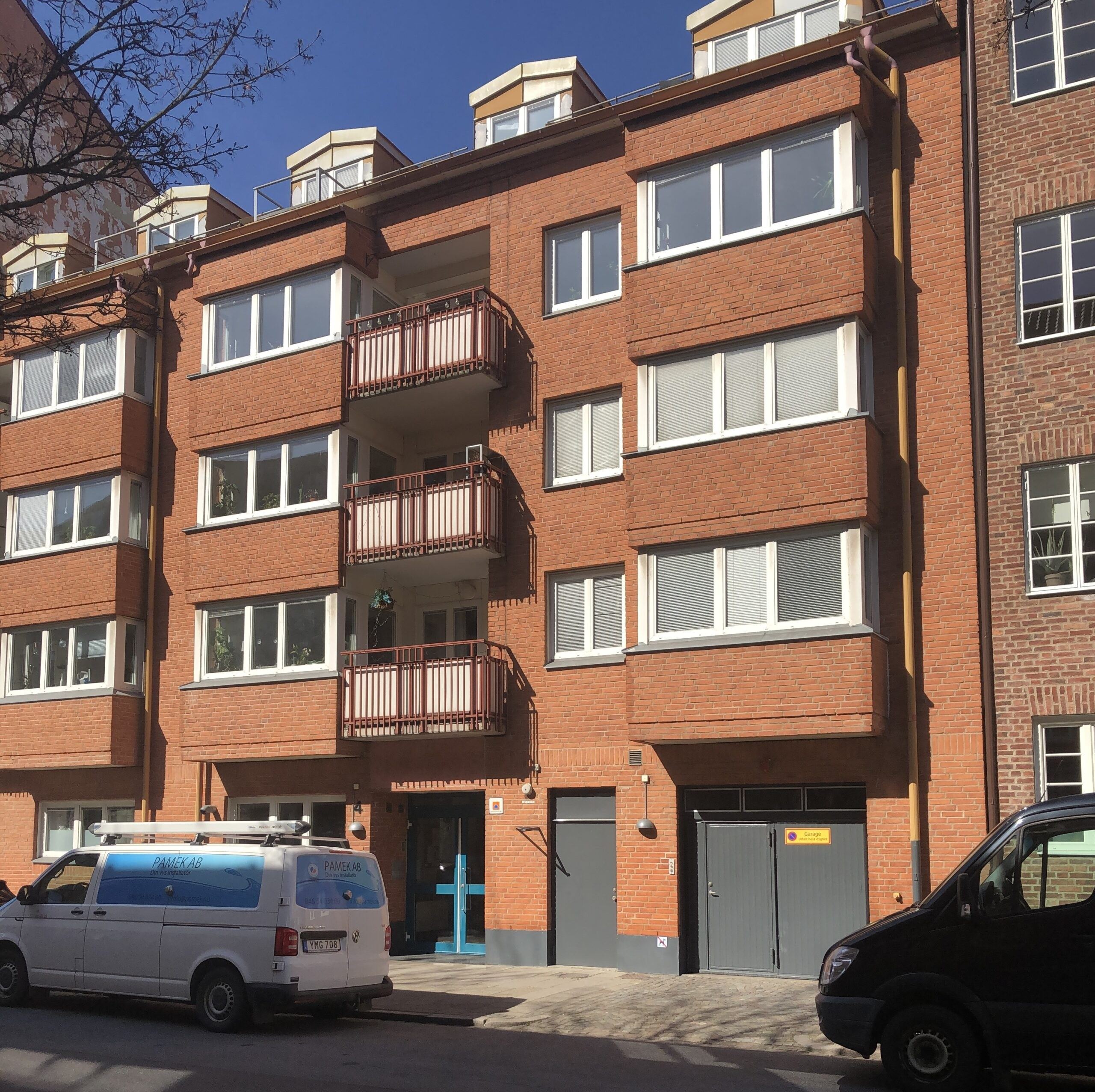 Ett rött tegelhus med balkonger och fönster, med en skåpbil på gatan