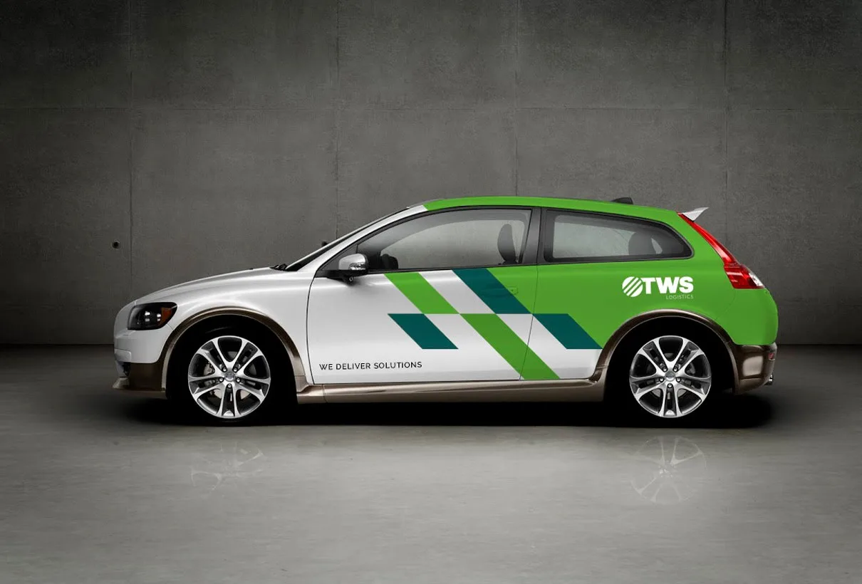 En vit personbil med grön och blå foliering och logotypen TWS, i ett grått rum